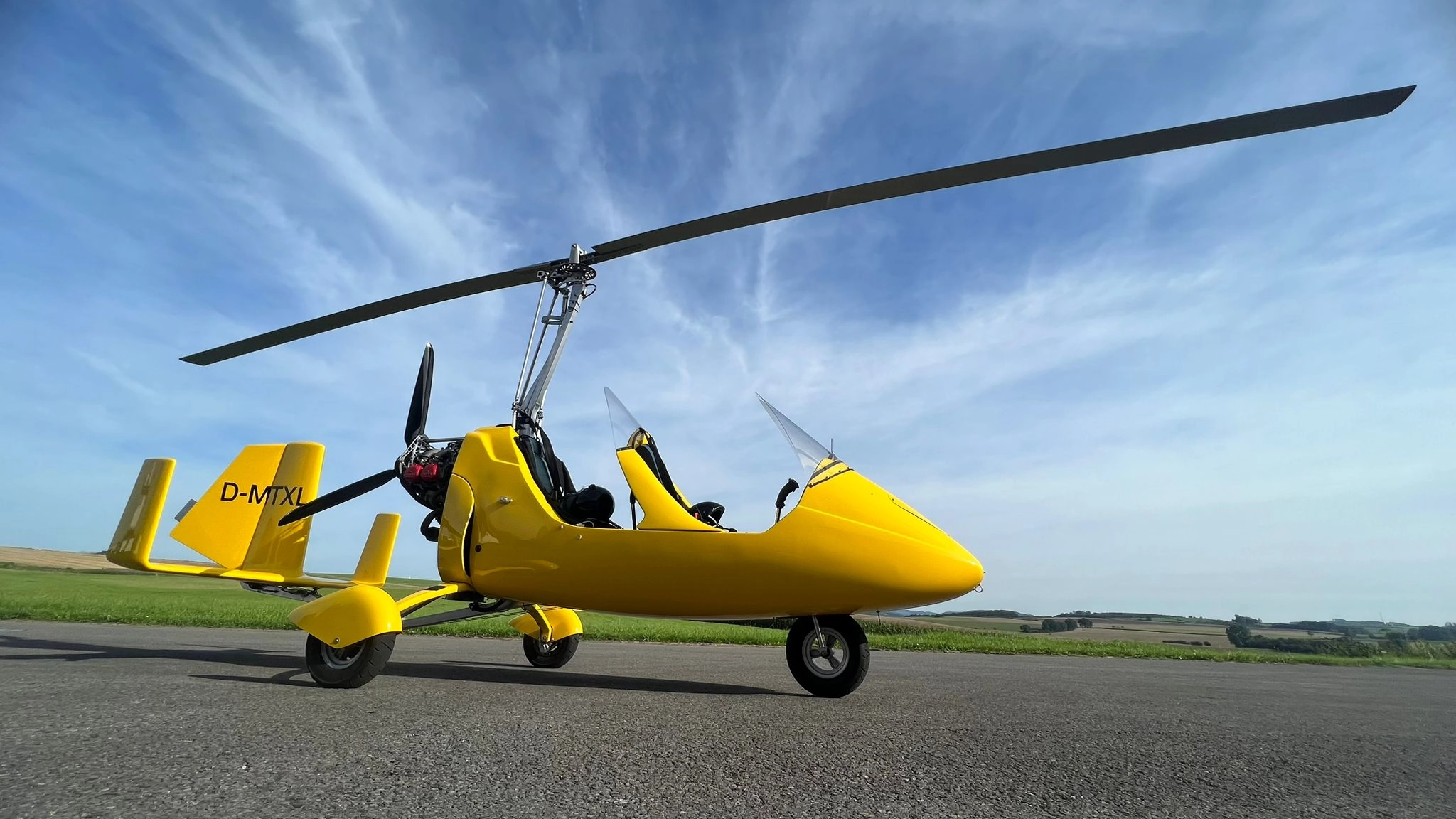 Gelber Tragschrauber (Gyrocopter) bei Sonnenschein am Flugplatz Meschede-Schüren